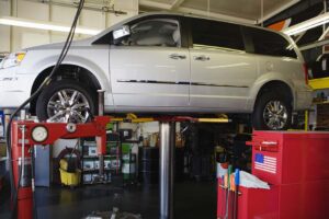 Minivan lifted up on repair stand in garage.