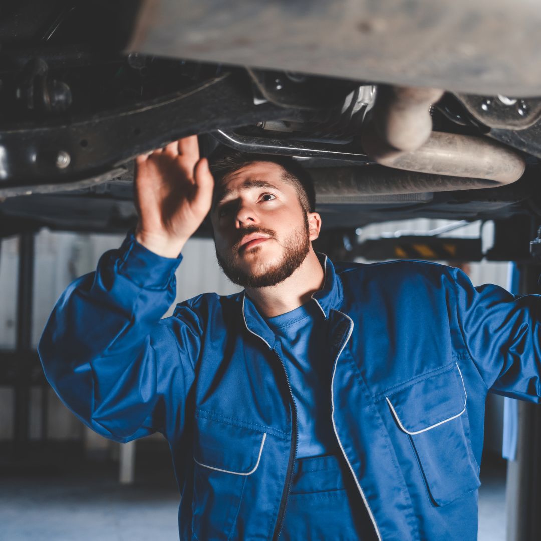 Mechanic inspecting underside of car